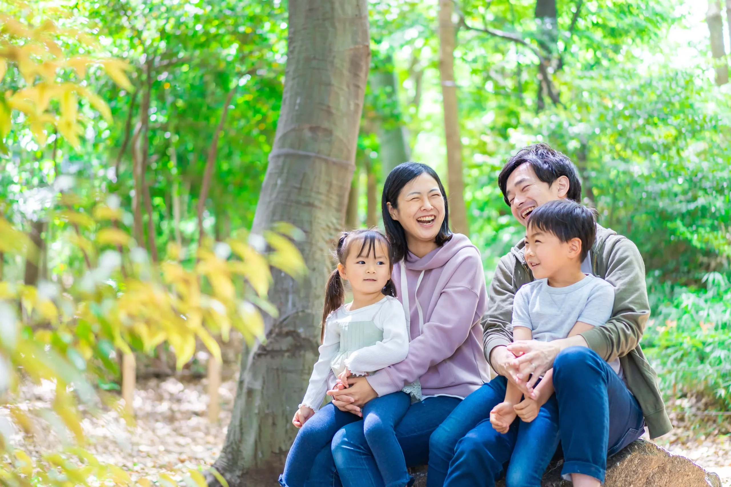 自然の中4人家族が仲良く笑っている